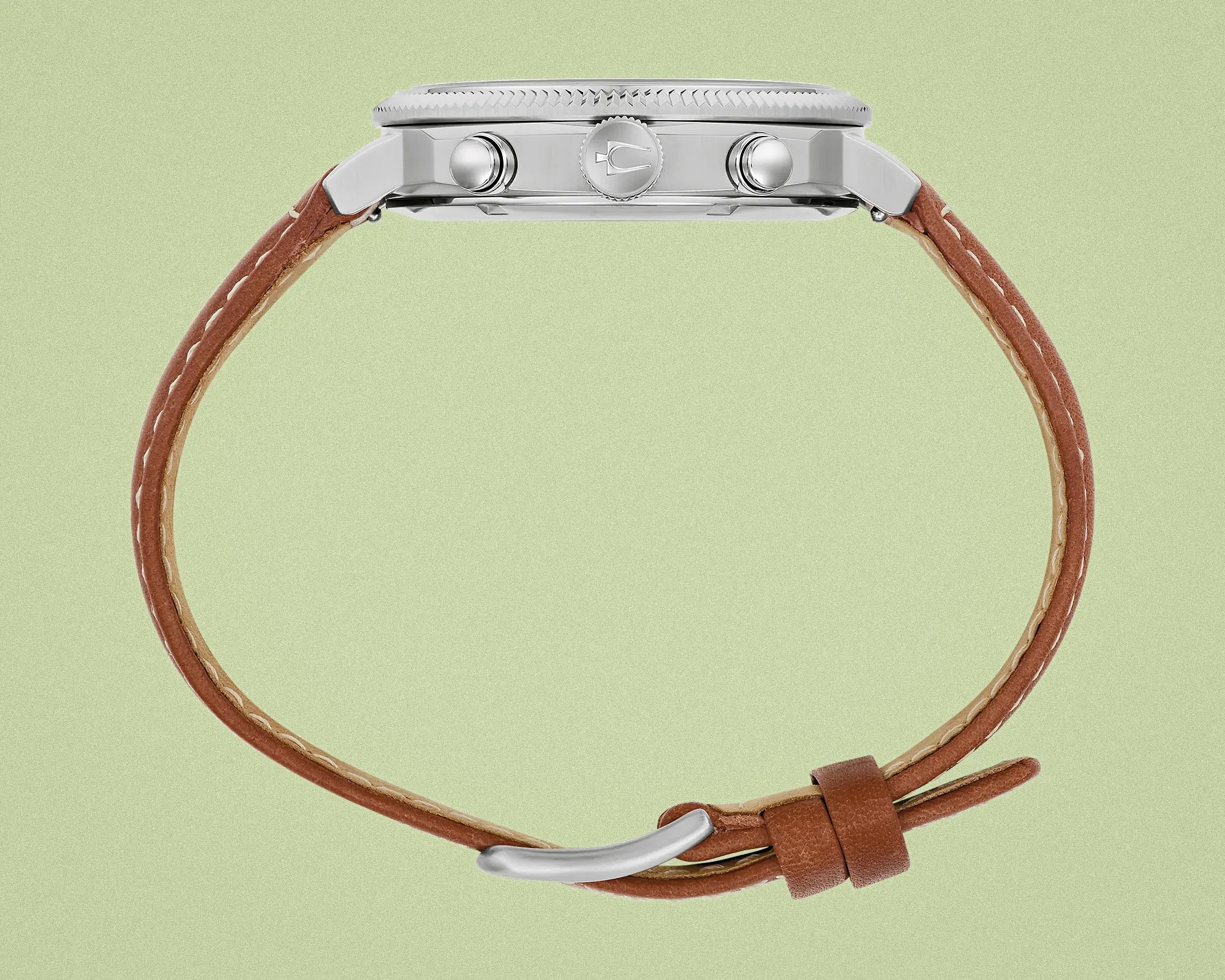 Side view of a silver watch case with two pushers and a crown, attached to a brown leather strap with white stitching.