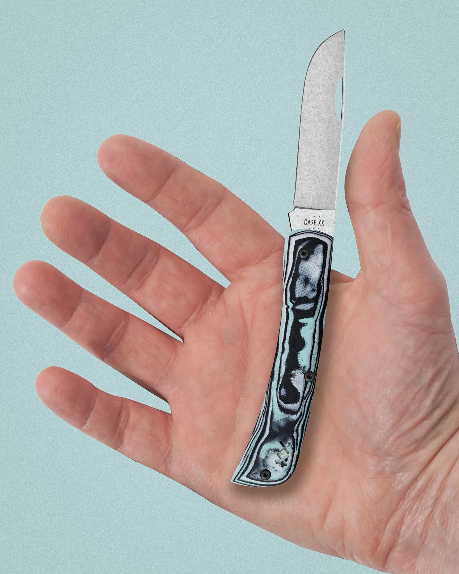 Small folding knife with a patterned handle and a partially open blade held in an open hand.