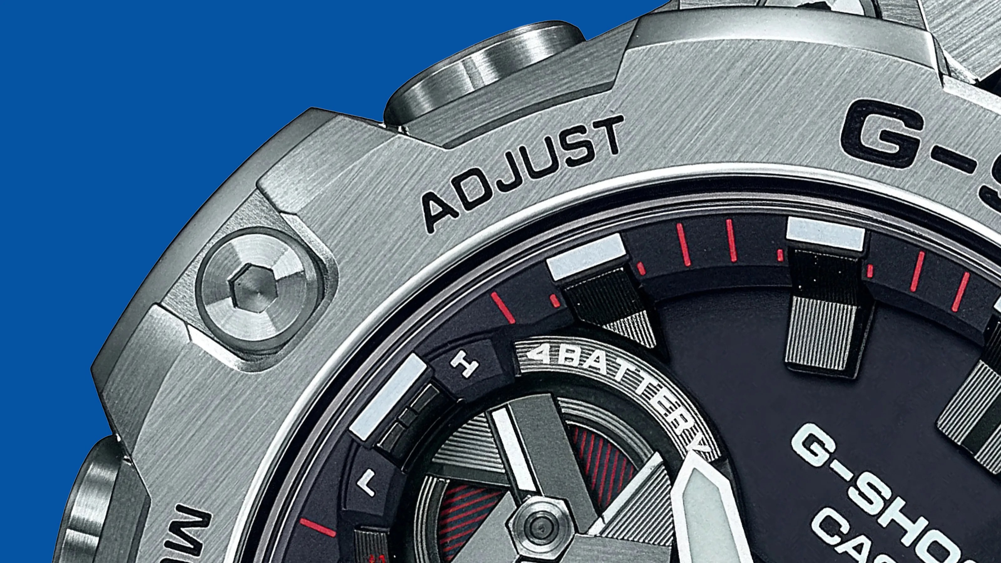 Close-up of a silver G-Shock Casio watch bezel and dial with "ADJUST" text and red and white markers.