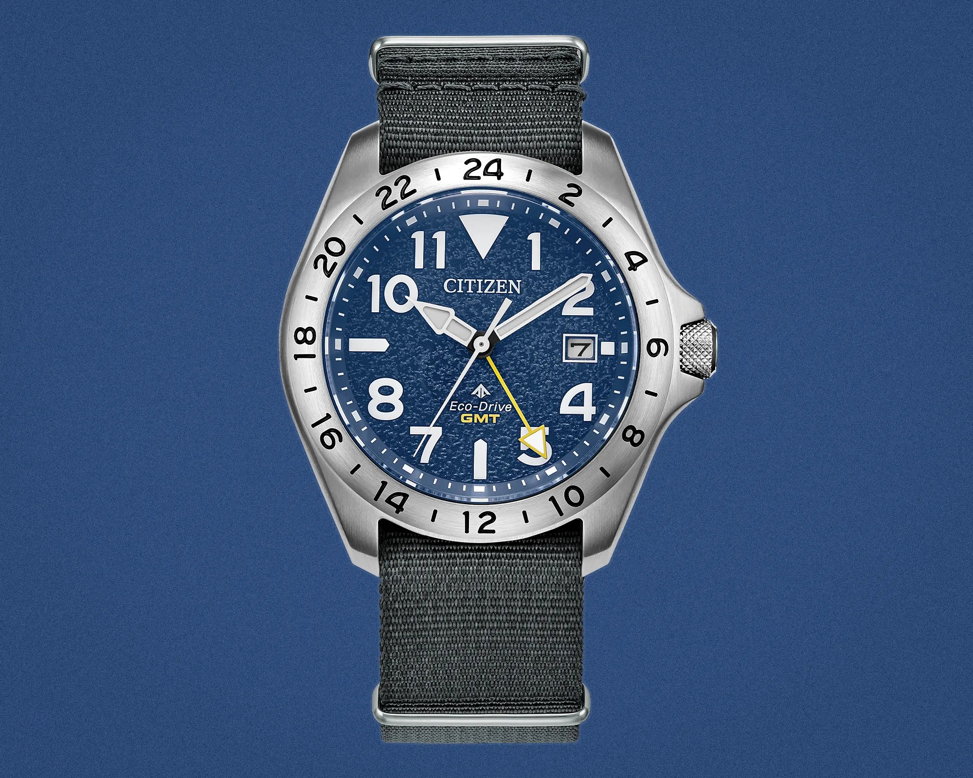 Citizen Eco-Drive GMT watch with blue textured dial, silver stainless steel case, and black fabric strap.