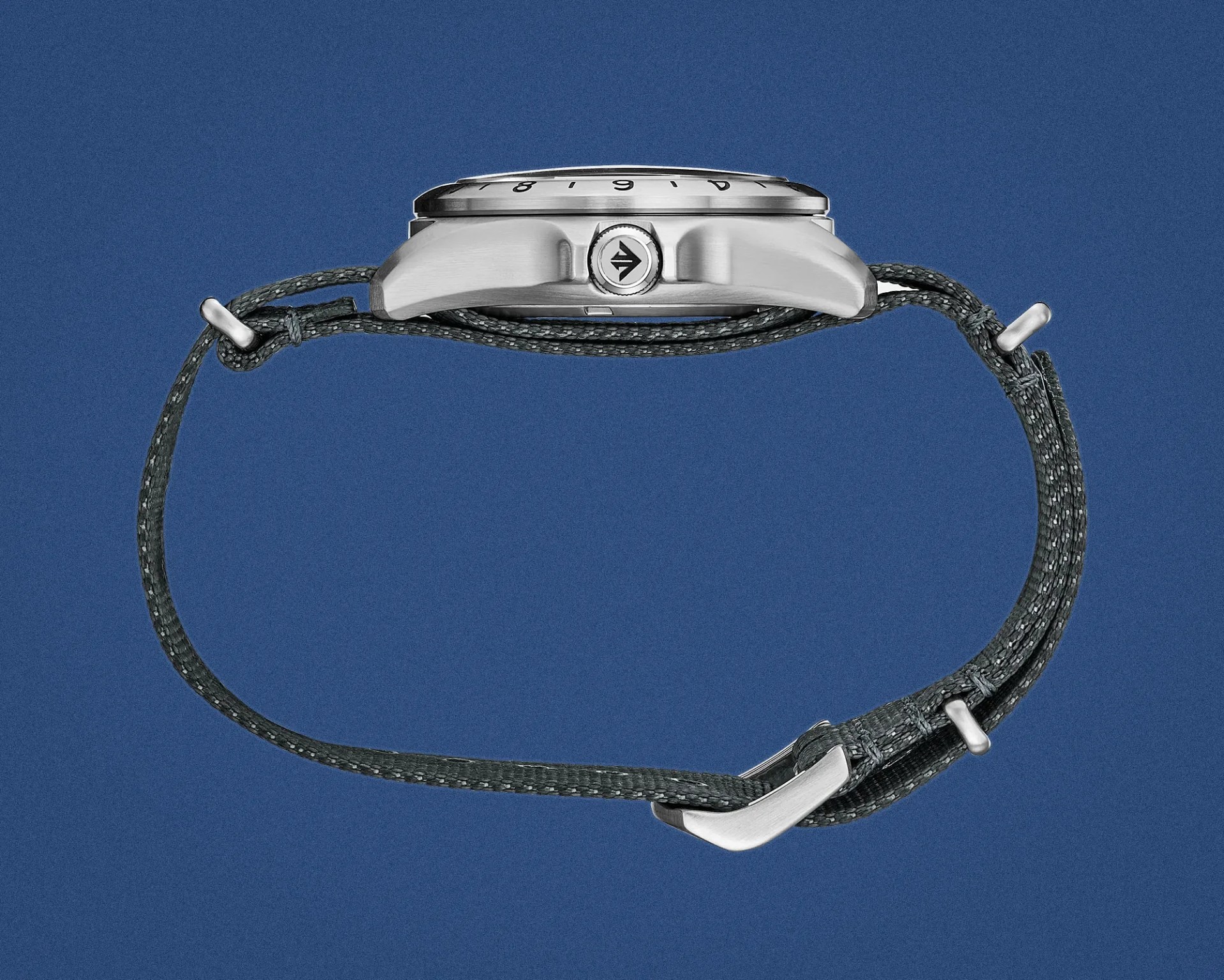 Side view of a silver wristwatch with a black woven strap against a blue background.