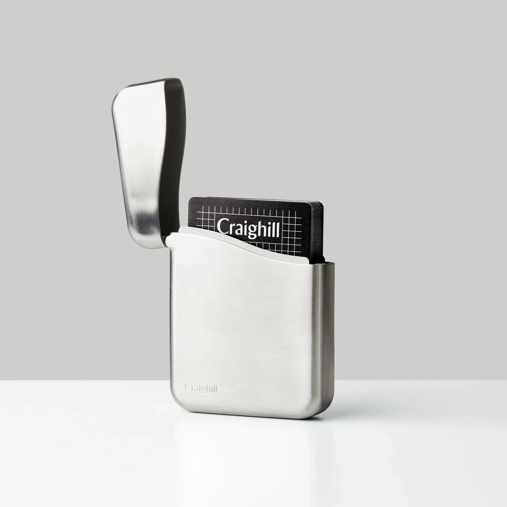 Brushed stainless steel card holder with an open hinged lid and a black card inside.