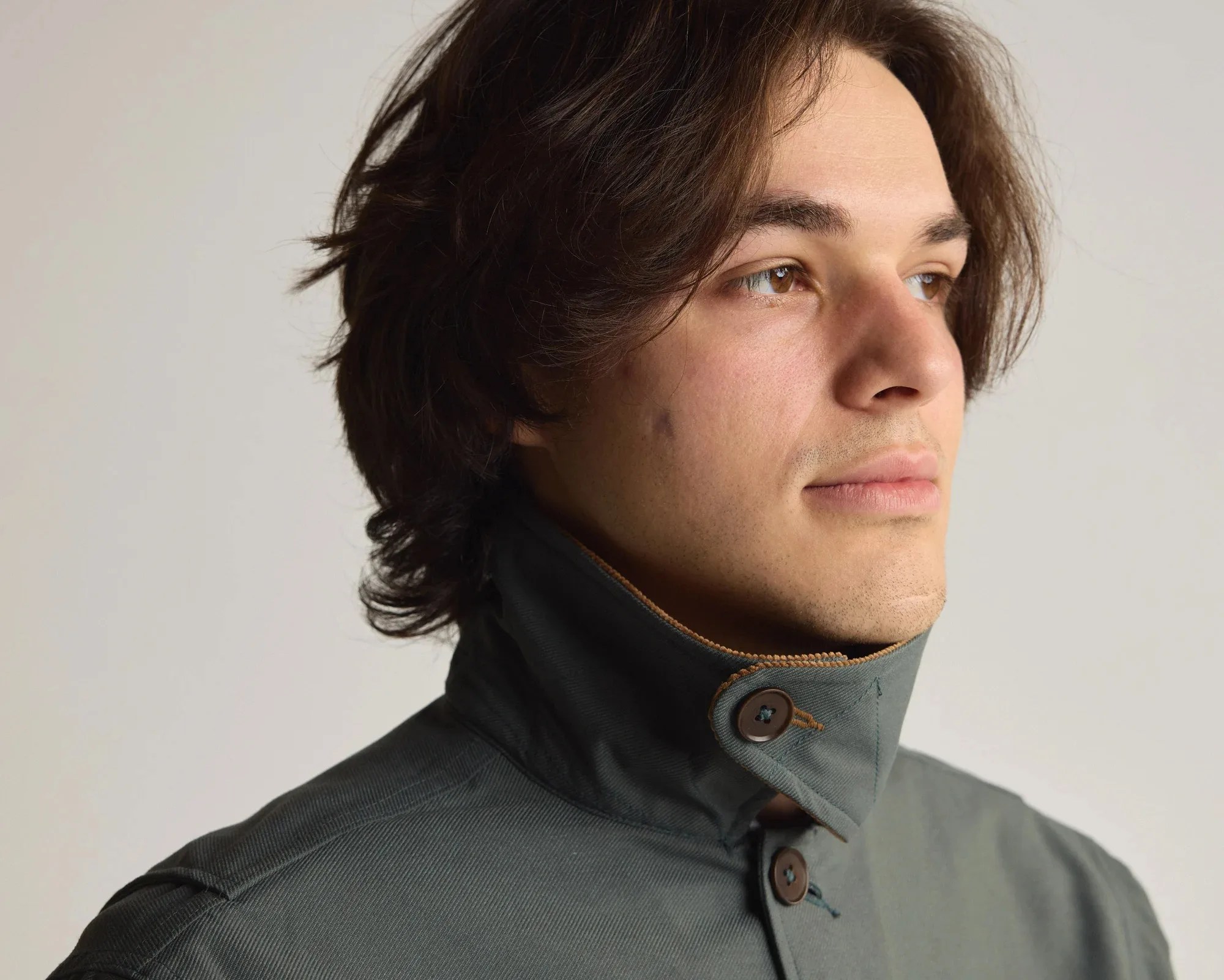 Close-up of a person wearing a dark green jacket with a high buttoned collar.
