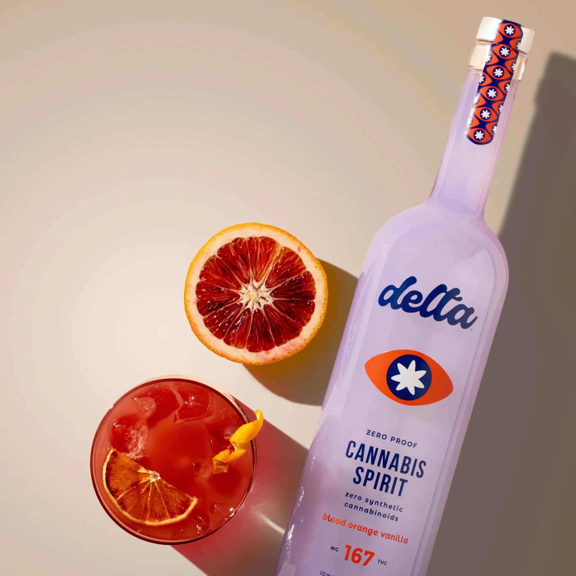 Lavender bottle of Delta Cannabis Spirit blood orange vanilla flavor next to a halved blood orange and a red cocktail with ice and citrus garnish.