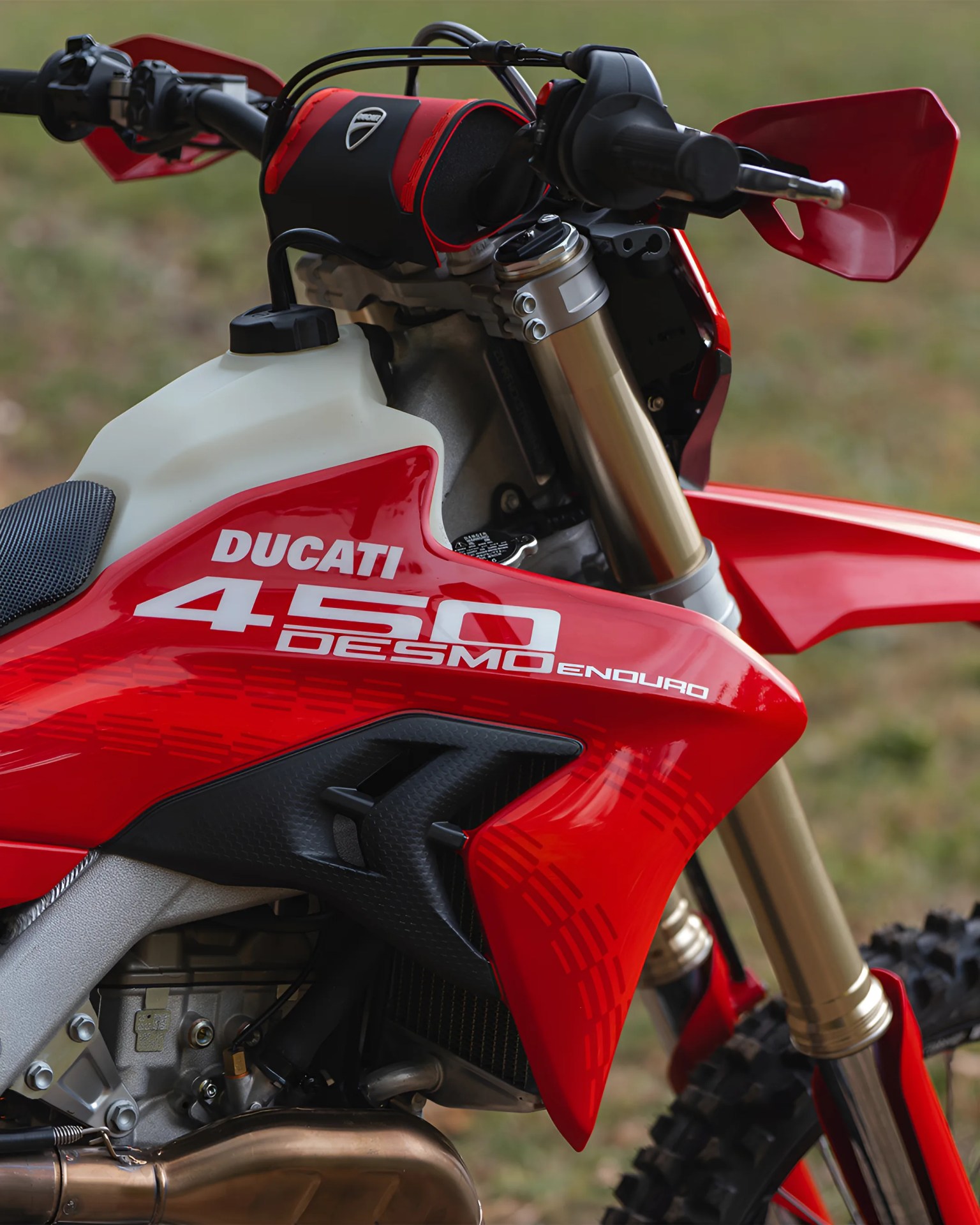 Red Ducati 450 Desmo Enduro dirt bike with gold front suspension forks and black handlebar grips.