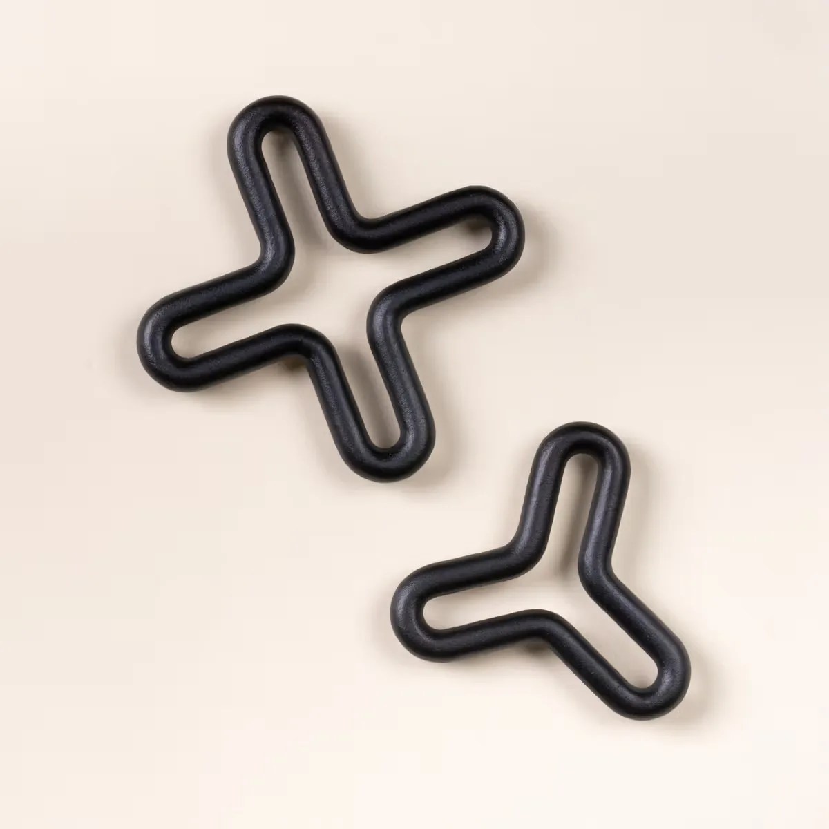 Two black rubber resistance bands shaped like a plus sign and a three-pronged star on a beige background.