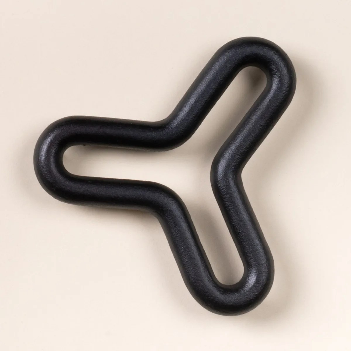 Black rubber-coated three-pronged hook with rounded edges on a beige background.