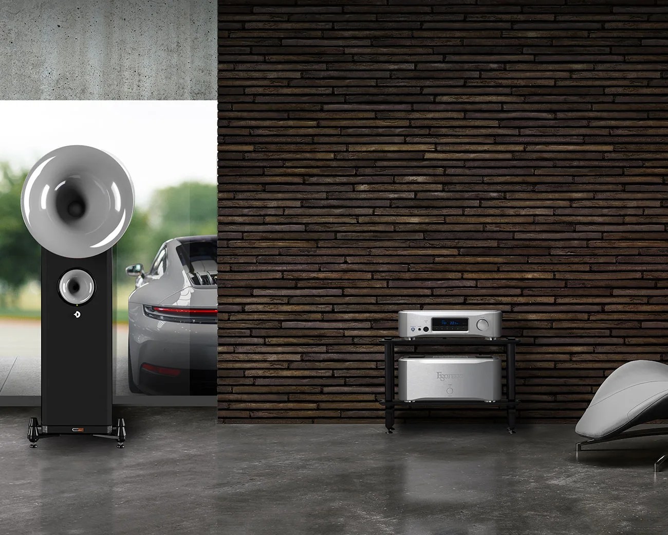 Black floor-standing horn speaker with silver horn and midrange driver next to a silver sports car, with silver audio equipment on a black stand against a dark wood wall.