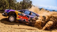 Rally car with Red Bull and Kenya HY logos kicking up dirt on a dusty off-road track.