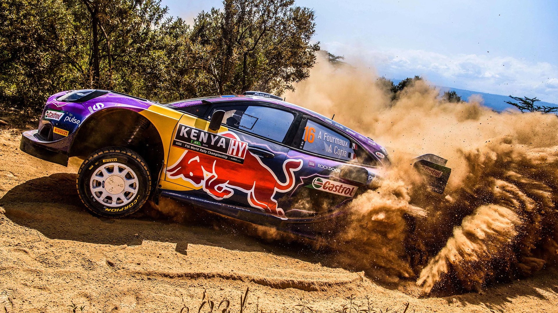 Rally car with Red Bull and Kenya HY logos kicking up dirt on a dusty off-road track.