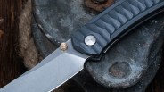 Close-up of a folding knife with a textured dark gray handle and a silver blade resting on a rusty metal surface.