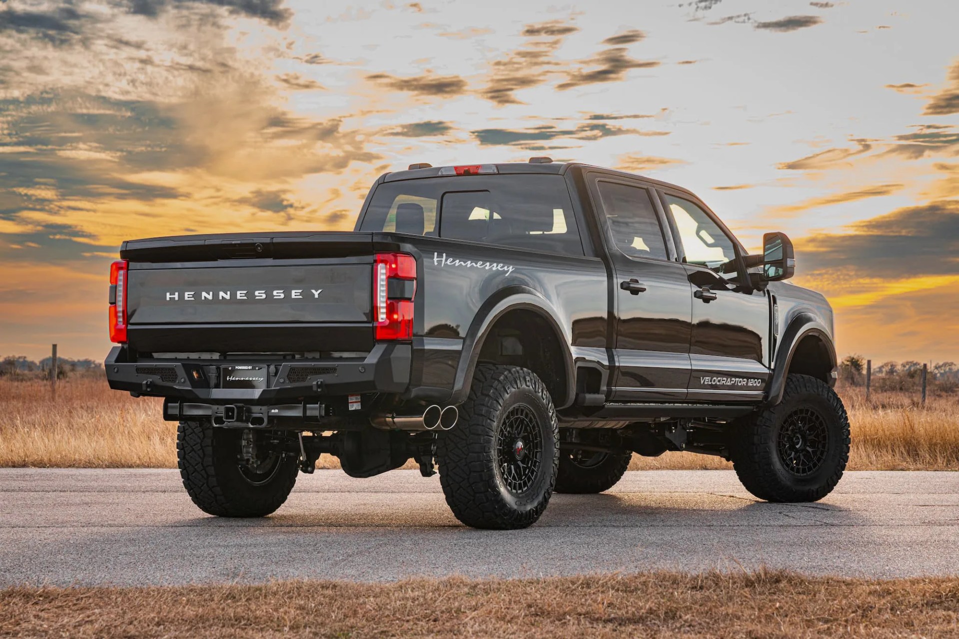Black Hennessey Velociraptor 1200 pickup truck parked on a road at sunset.