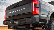 Rear view of a black Hennessey pickup truck with red taillights, dual exhaust pipes, and rugged tires.