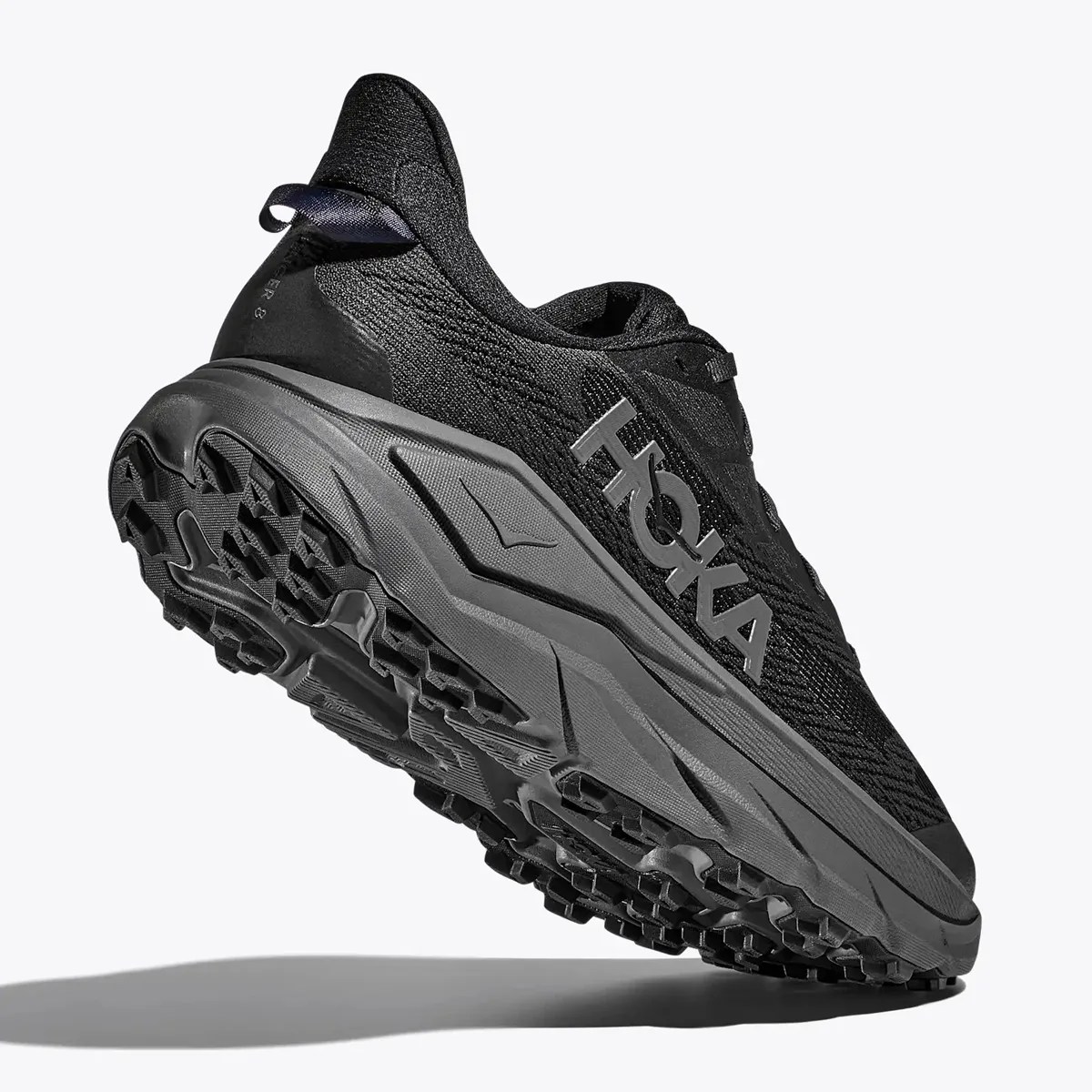 Black Hoka running shoe with thick gray sole and textured tread, shown from a low rear angle.