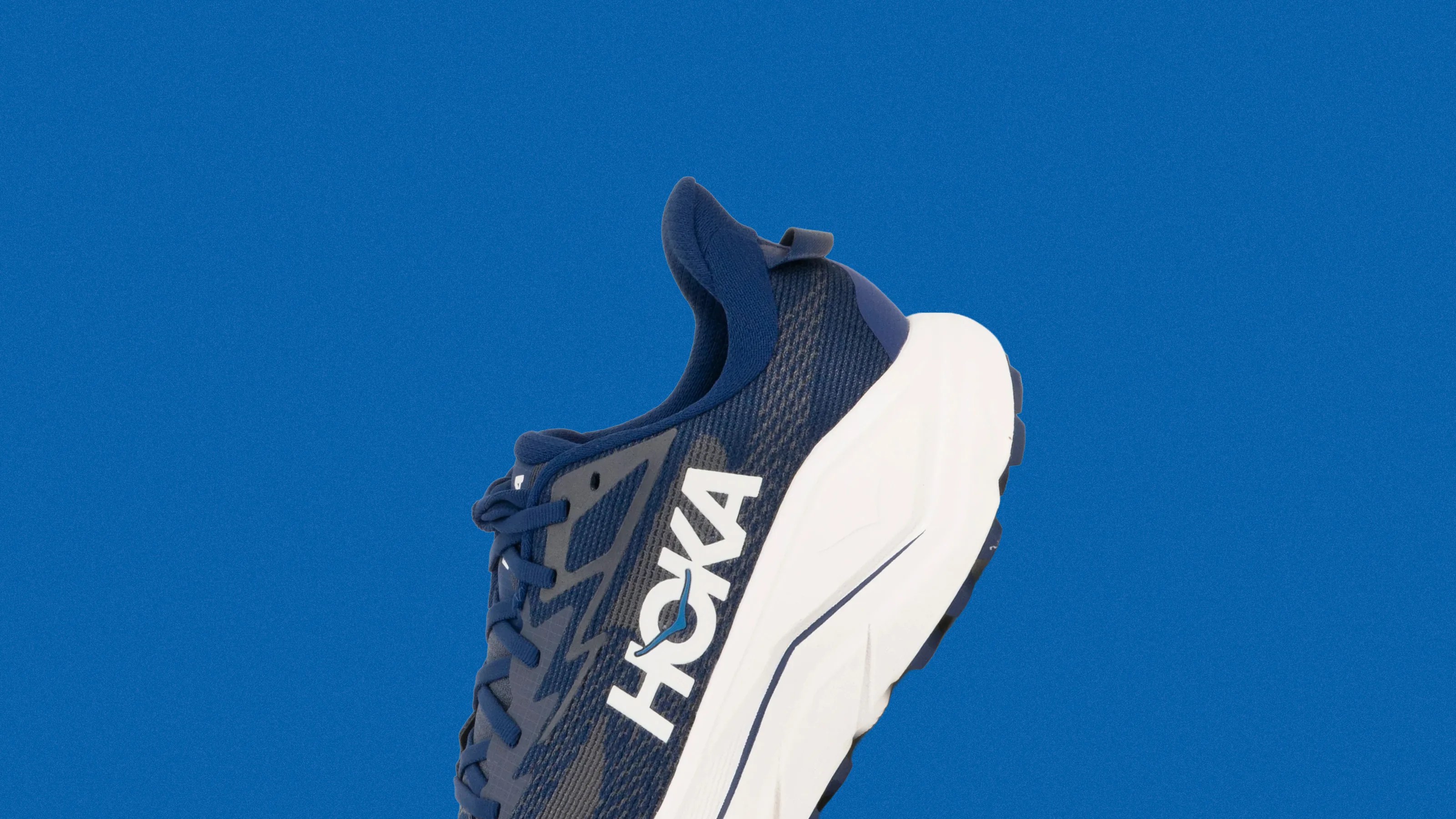 Navy blue Hoka running shoe with white sole against a solid blue background.