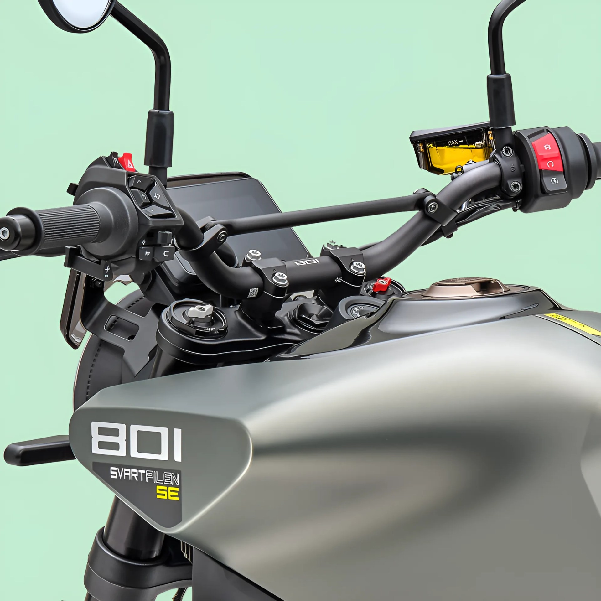 Close-up of matte gray Svartpilen 801 SE motorcycle fuel tank and black handlebars with controls against a light green background.