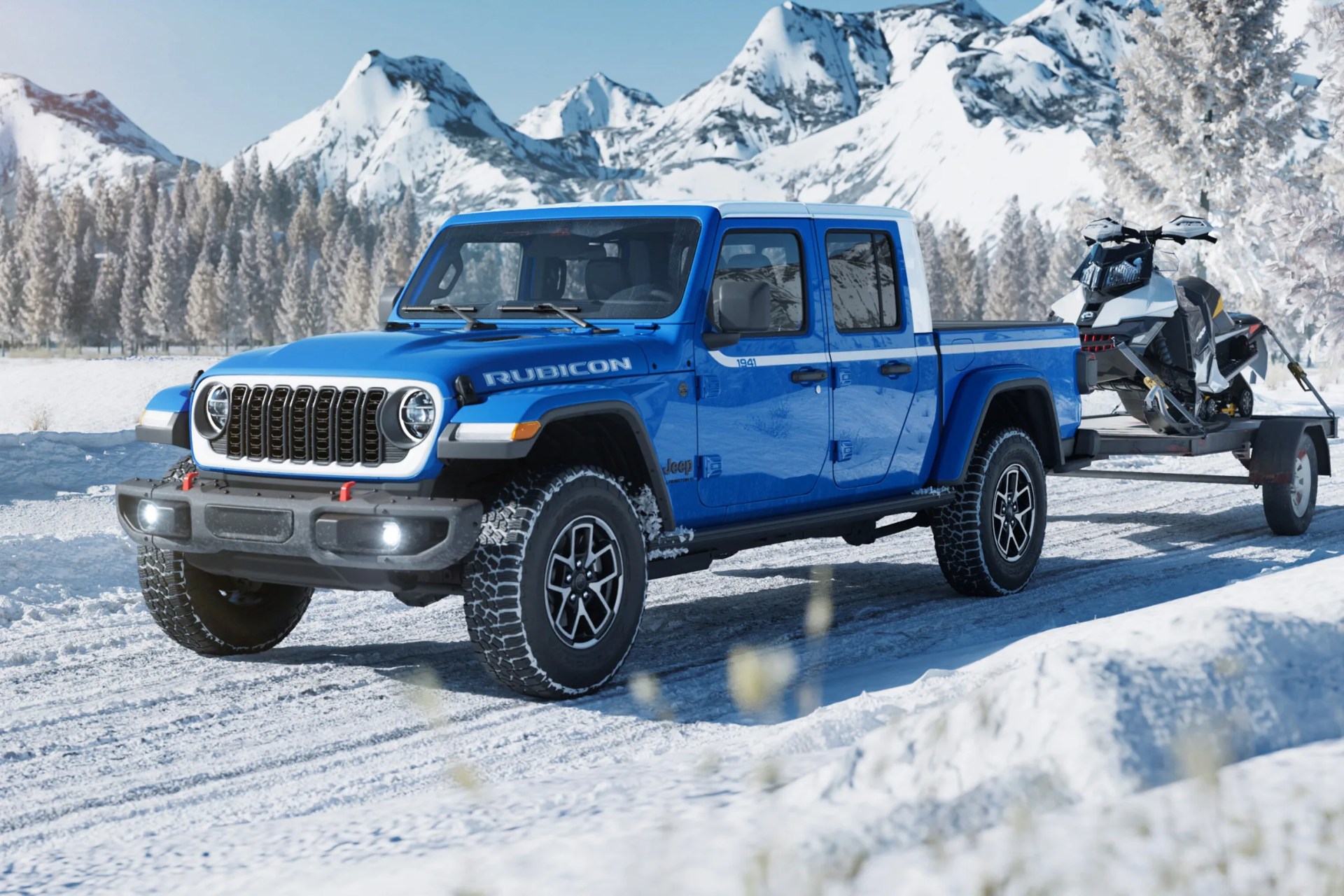 Blue Jeep Gladiator Rubicon pickup truck towing a snowmobile on a trailer in a snowy mountain landscape.