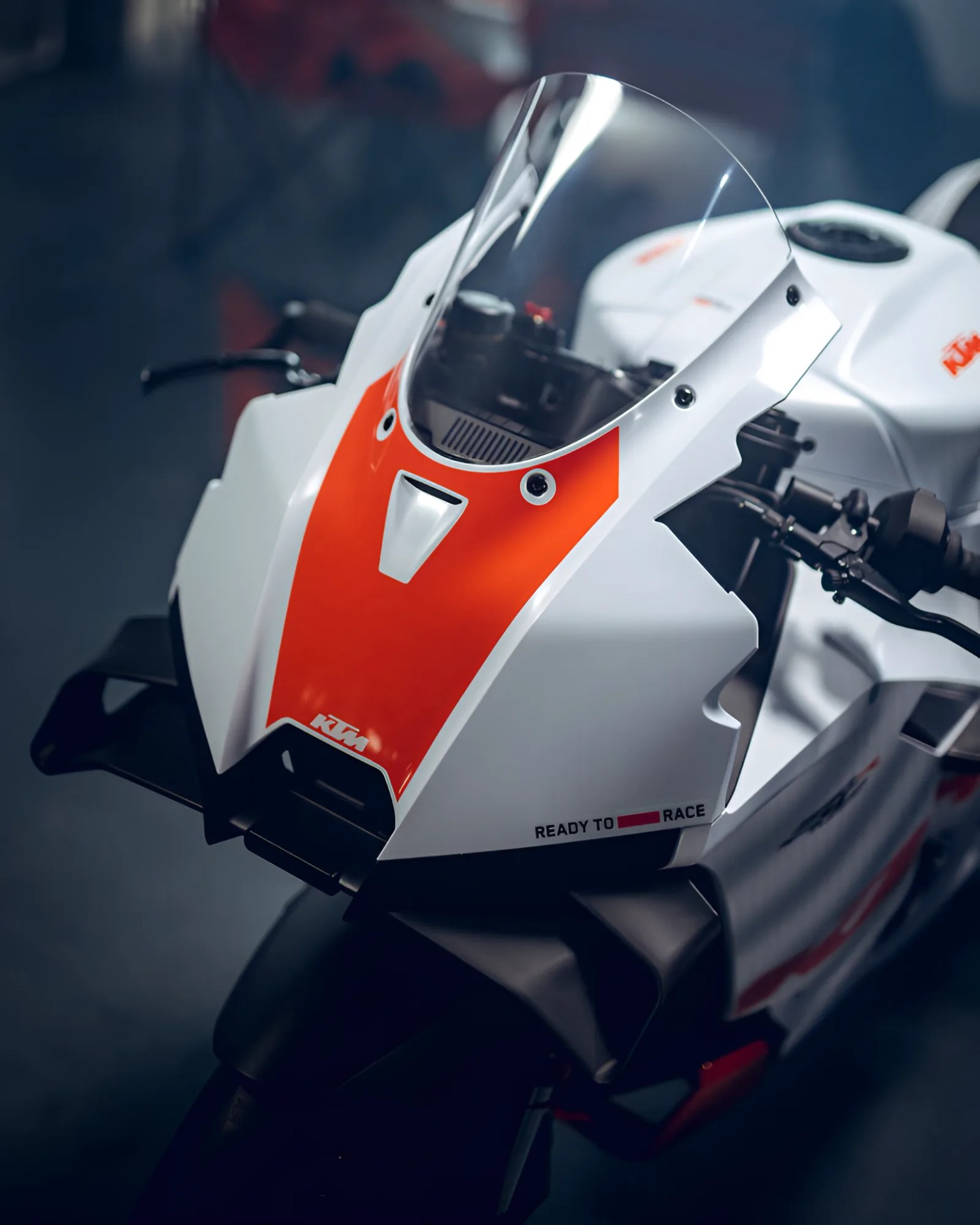 White and orange KTM sport motorcycle front with clear windshield and "Ready to Race" text.