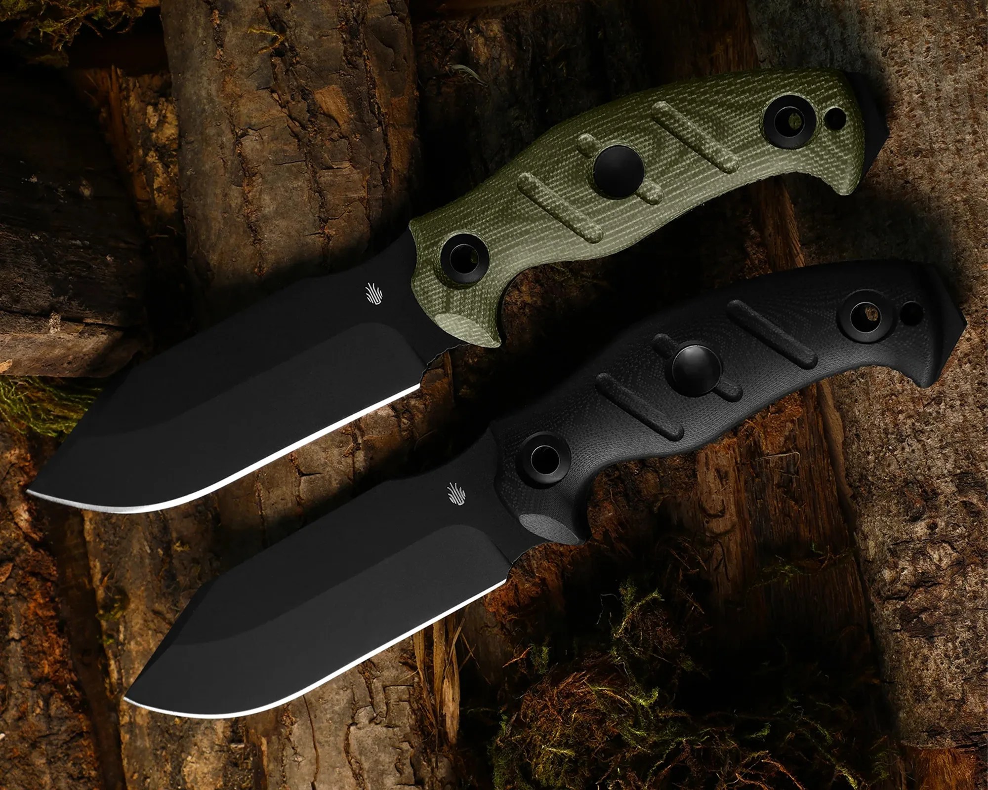 Two fixed-blade knives with black blades and textured handles, one olive green and one black, on a wood surface.