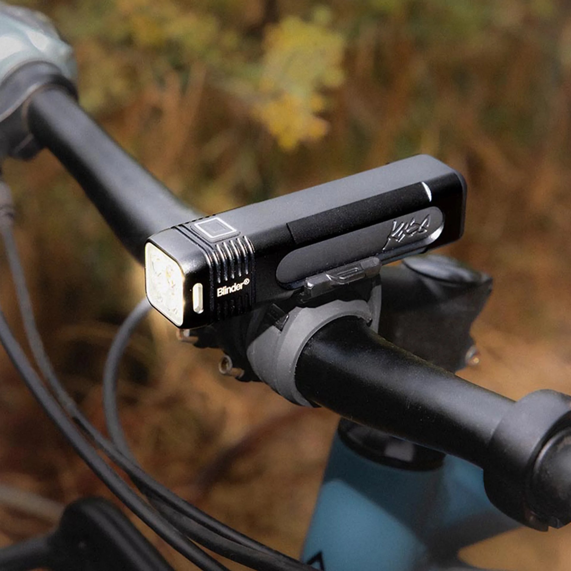 Black rectangular bike headlight labeled "Blinder" mounted on a black handlebar.