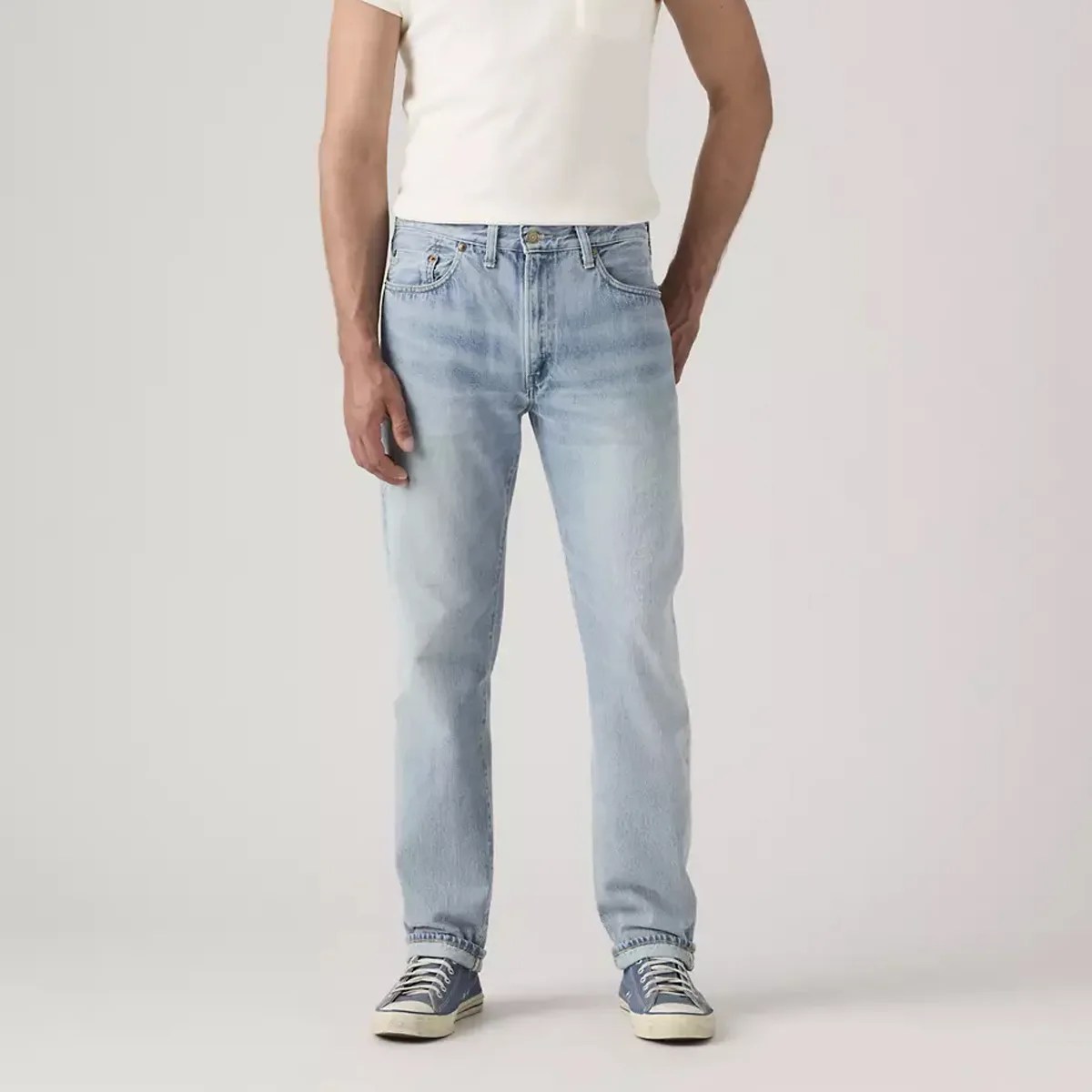 Light blue straight-leg jeans worn with blue sneakers and a white short-sleeve shirt.