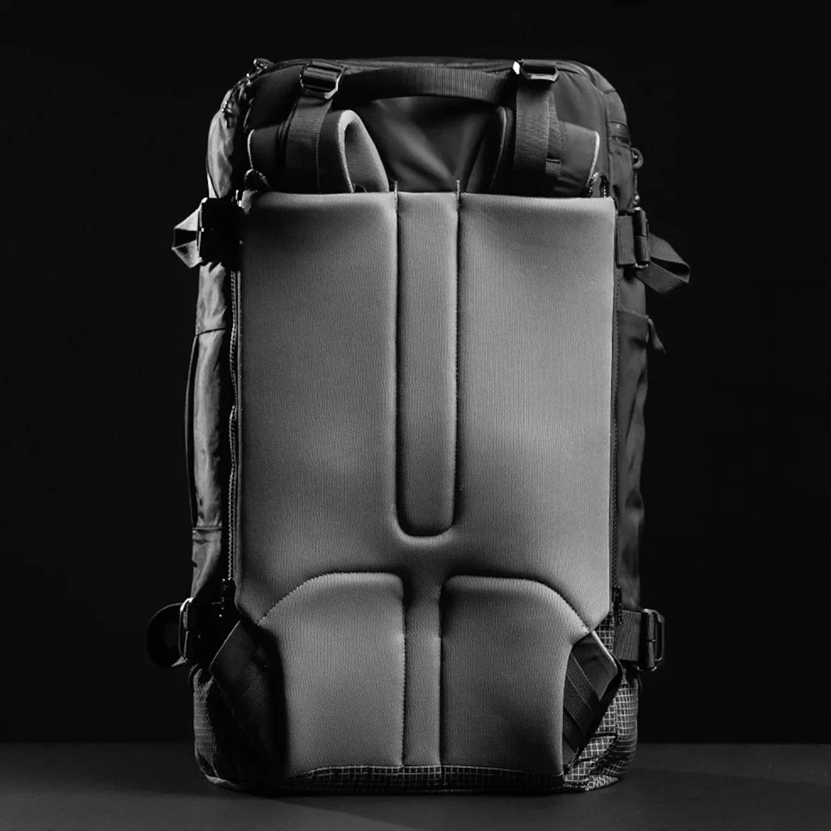 Black and gray backpack with padded back panel and adjustable straps on a dark background.