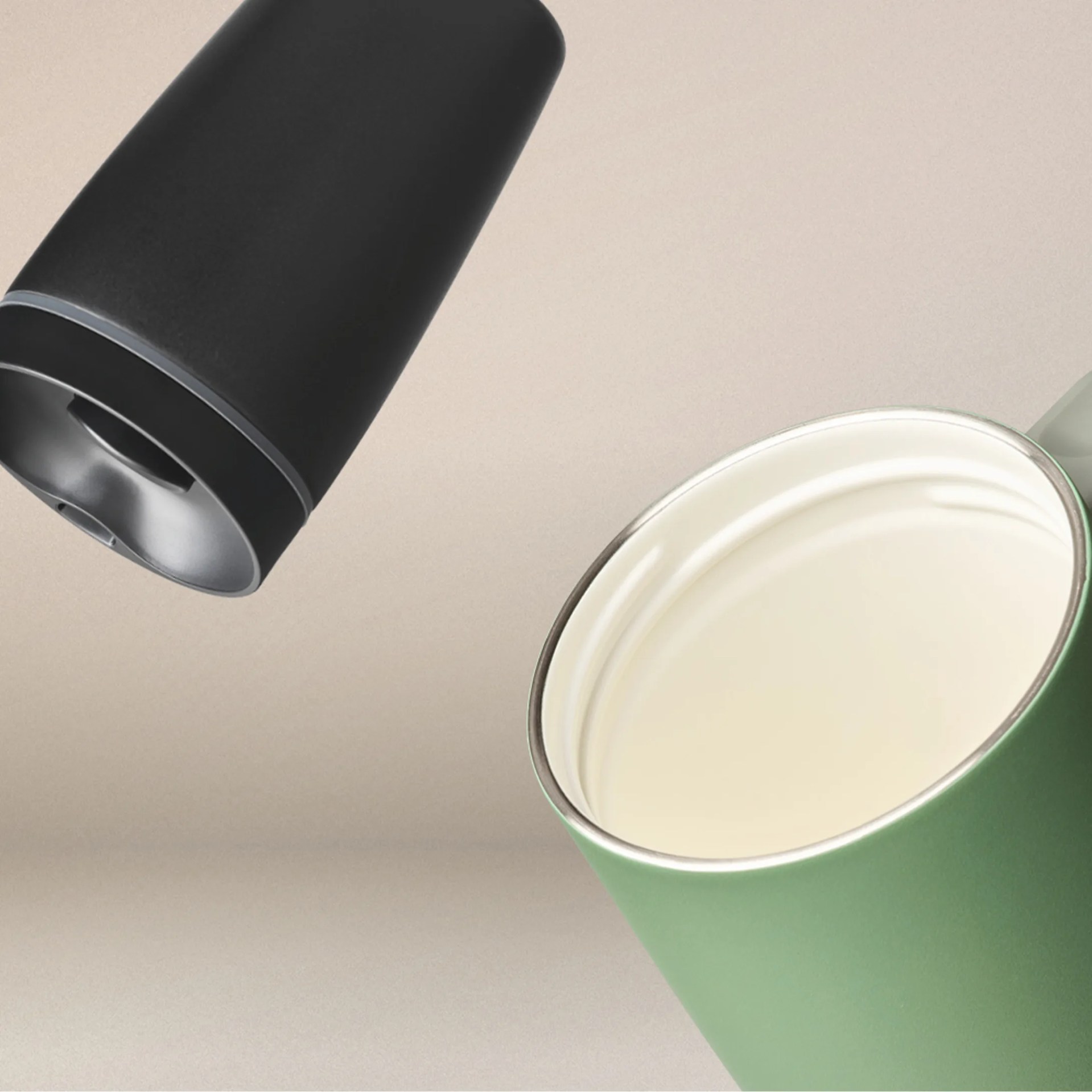 Green enamel mug with a silver rim and a black insulated travel mug lid above it.