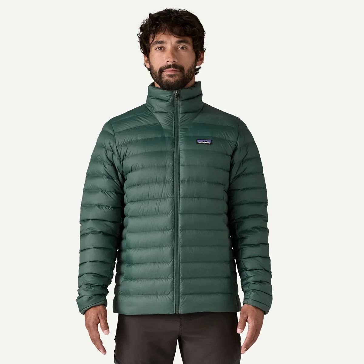 Dark green quilted Patagonia puffer jacket with a front zipper worn by a person.