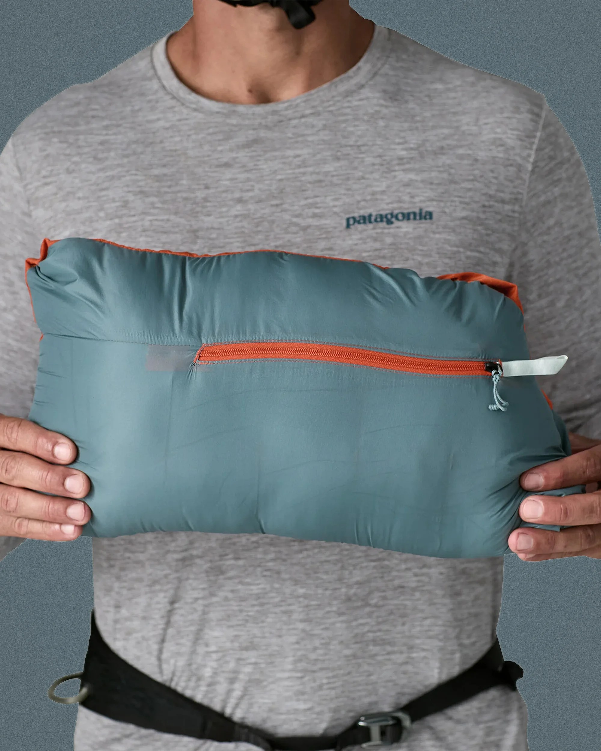 Teal and orange zippered stuff sack held by a person wearing a grey Patagonia shirt.