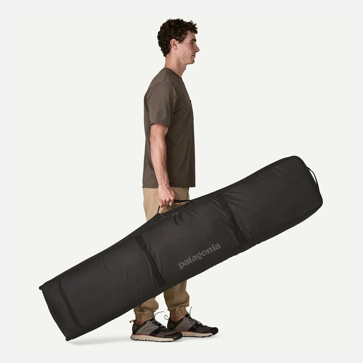 Black Patagonia padded ski bag with handle held by a person standing in profile.