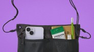 Black drawstring pouch with front mesh pockets holding a white smartphone, Patagonia snack pack, notebook, green pencil, and small bottle.