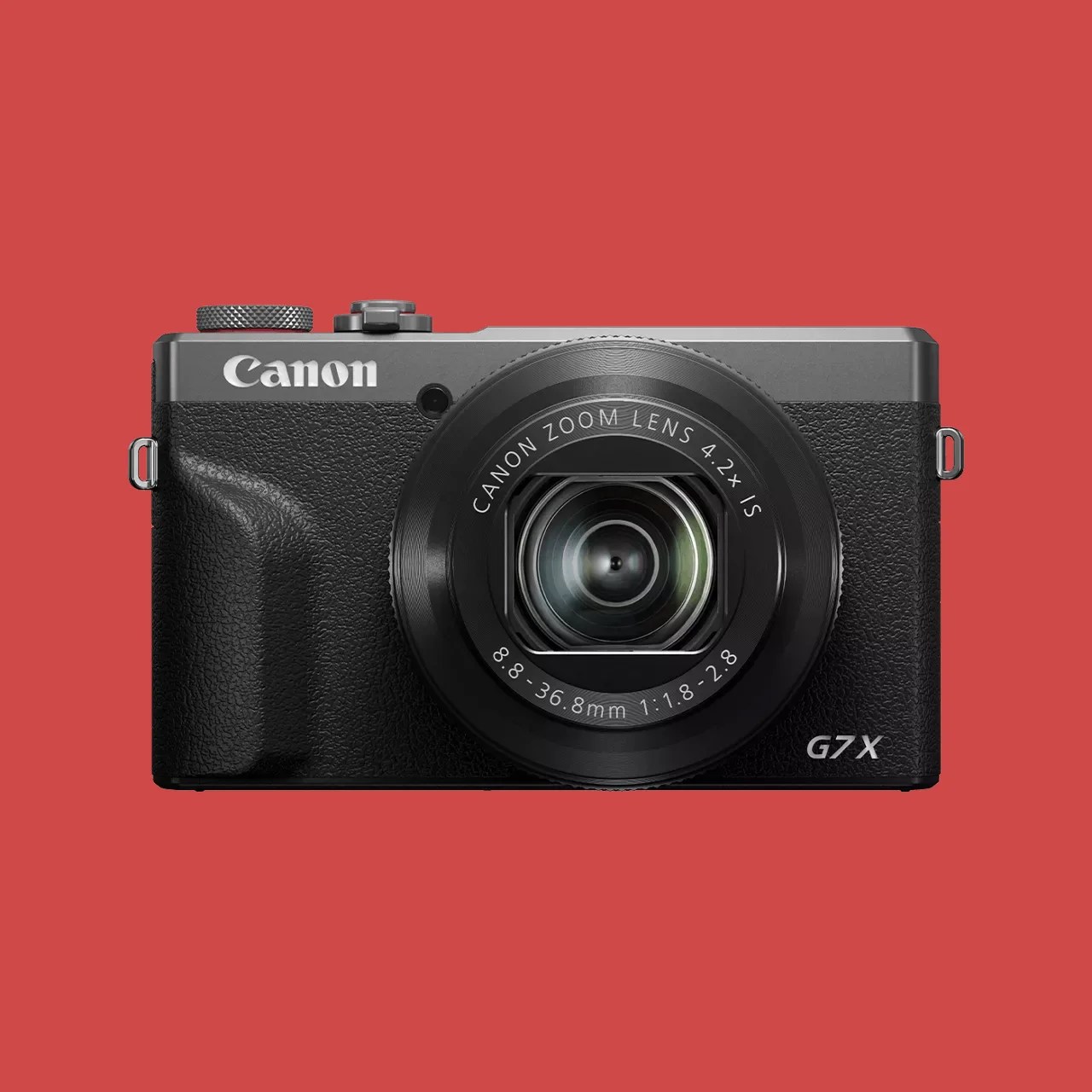 Black and silver Canon G7X compact digital camera with zoom lens on a red background.