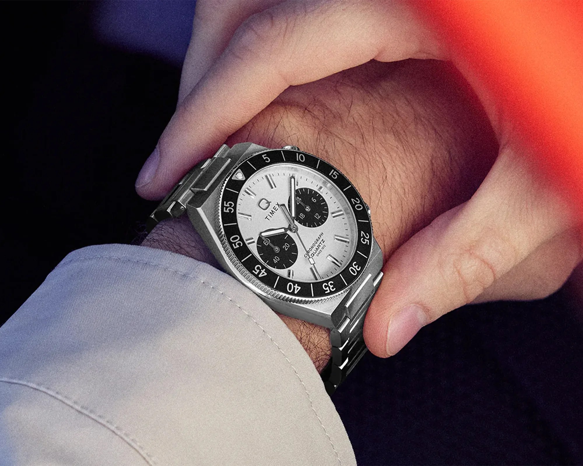 Silver Timex chronograph wristwatch with black bezel and two black subdials on a metal bracelet worn on a wrist.