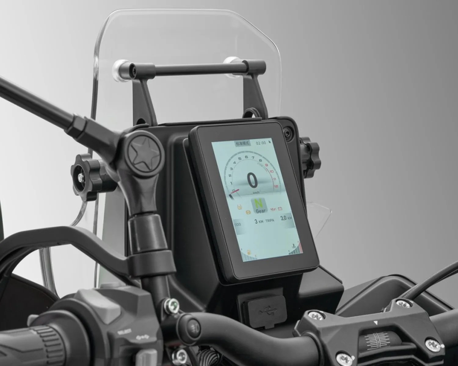 Motorcycle digital dashboard display showing speedometer, gear indicator, and trip information with a clear windshield in the background.