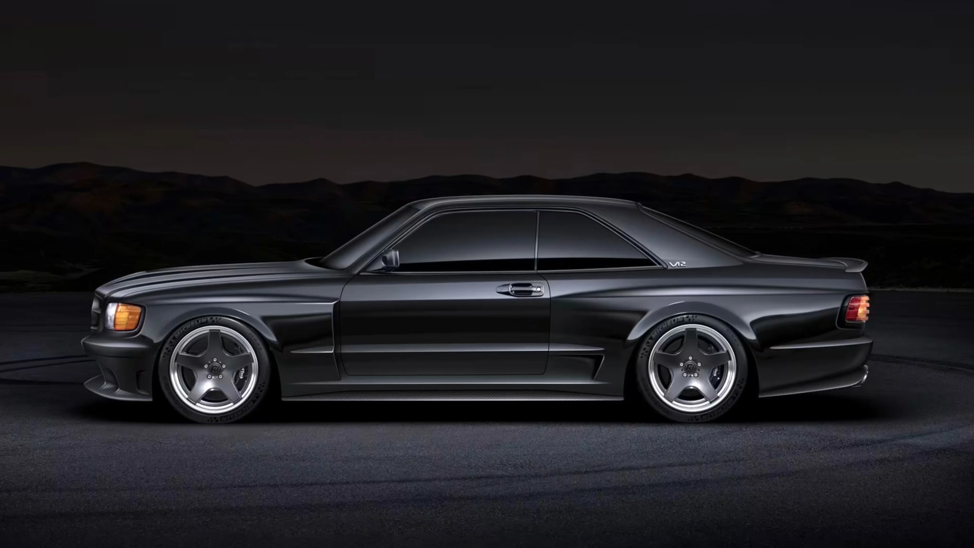 Sleek black two-door coupe with tinted windows, V12 badge, and five-spoke silver alloy wheels on dark pavement.