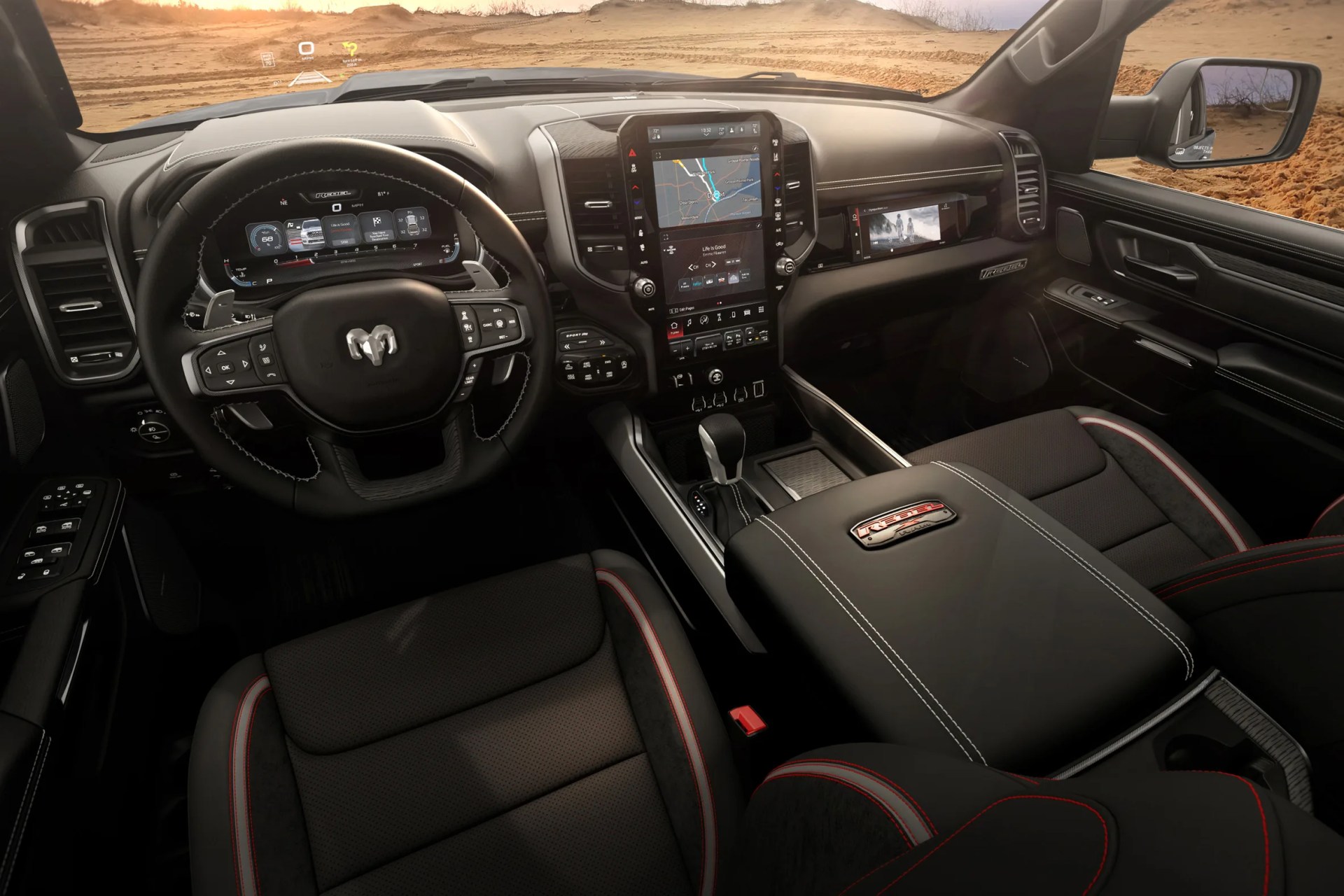 Black leather and fabric truck interior with red stitching, digital dashboard, large central touchscreen, and "Rebel" emblem on center console.