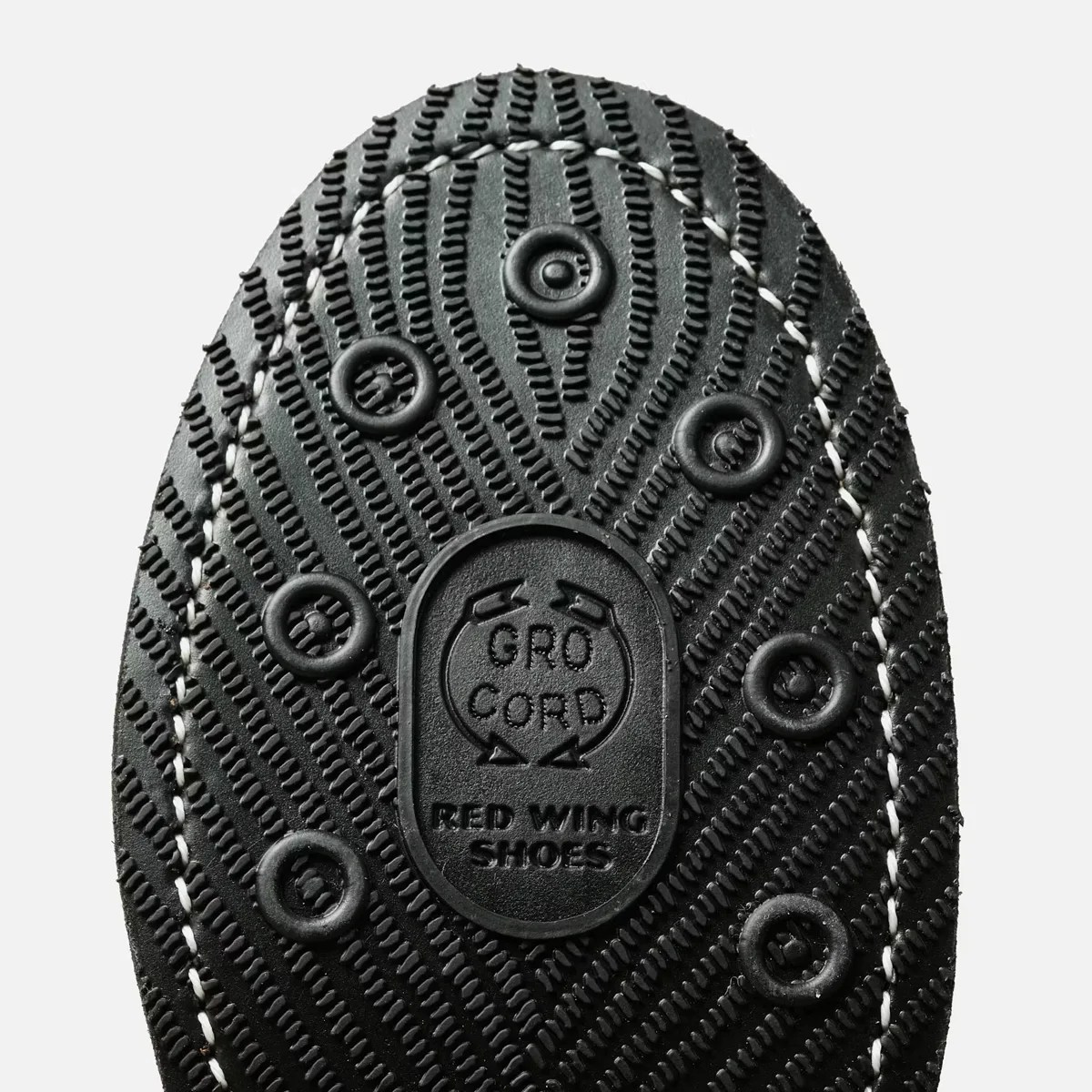 Close-up of a black rubber shoe sole with circular treads and "GRO CORD RED WING SHOES" embossed in the center.