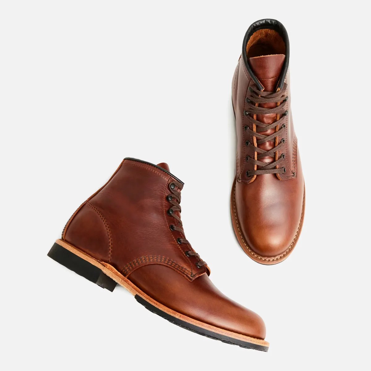 Pair of brown leather lace-up boots with black soles and tan stitching on a white background.
