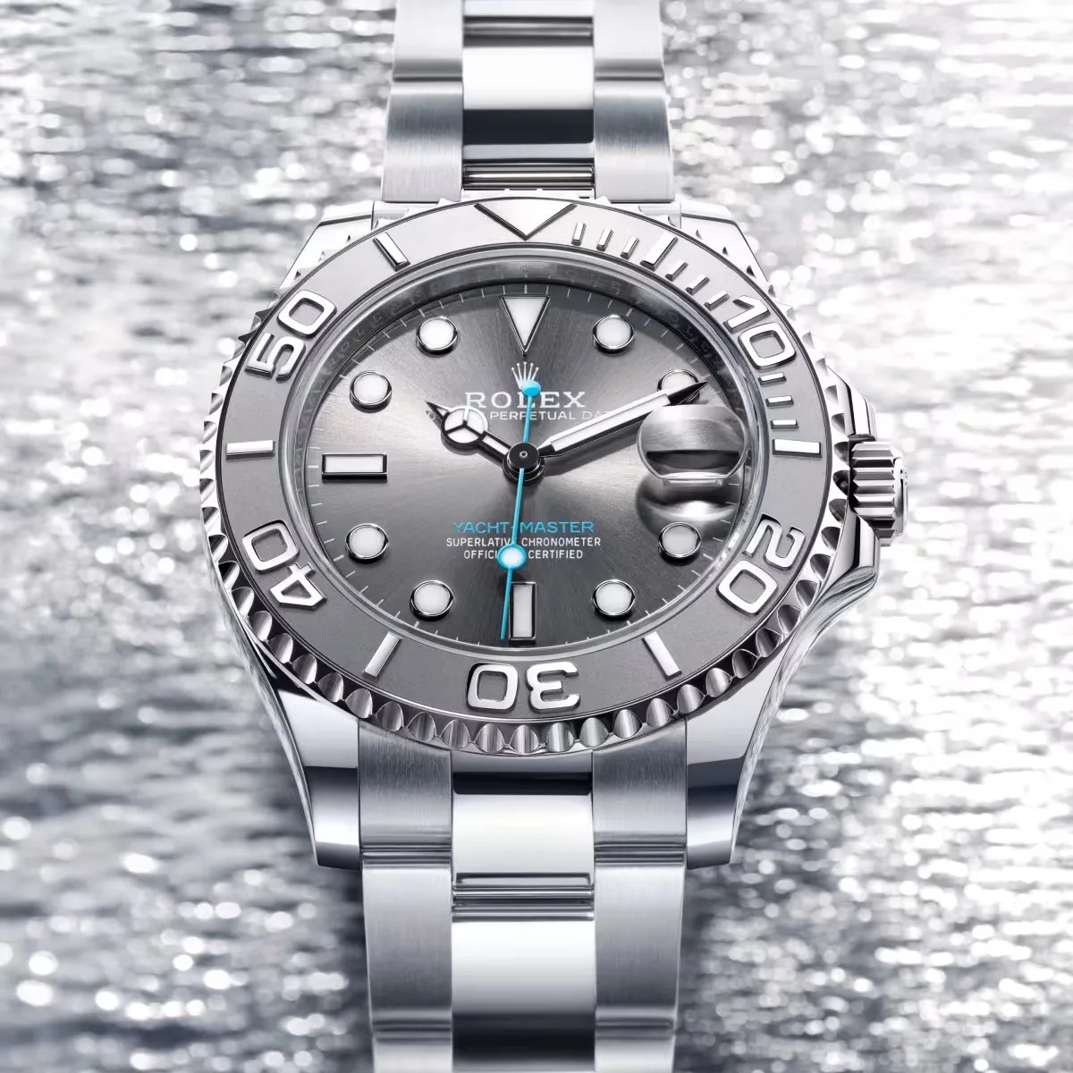 Silver Rolex Yacht-Master watch with a metallic gray dial and blue second hand on a matching silver bracelet.