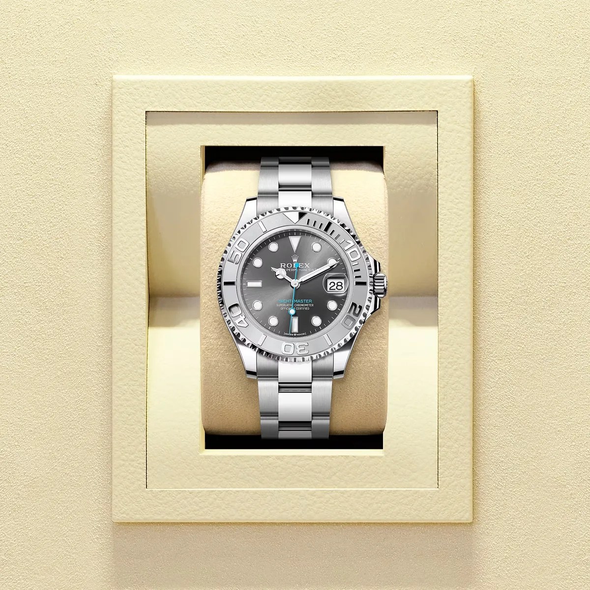 Silver Rolex Yacht-Master watch with a gray dial and date display on a beige cushion inside a cream-colored box.
