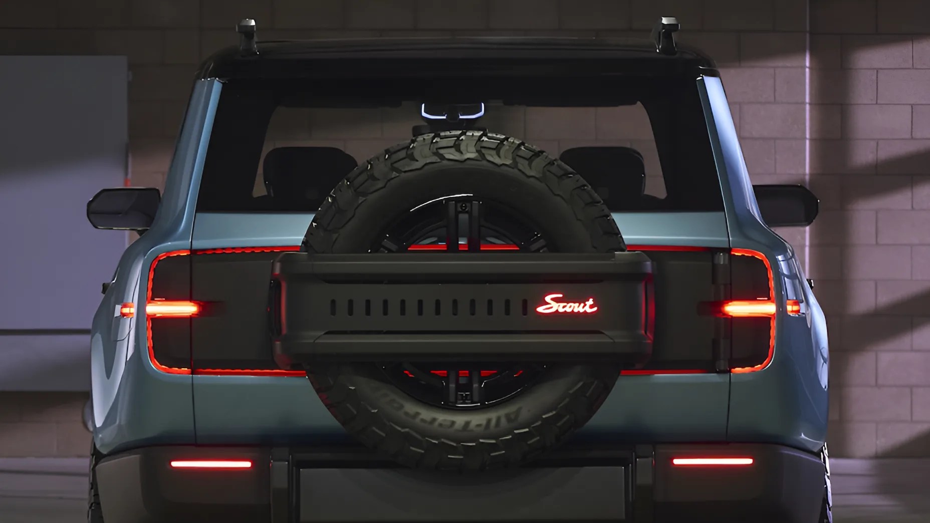 Rear view of a blue Scout SUV with a spare tire mounted on the back and illuminated red taillights.