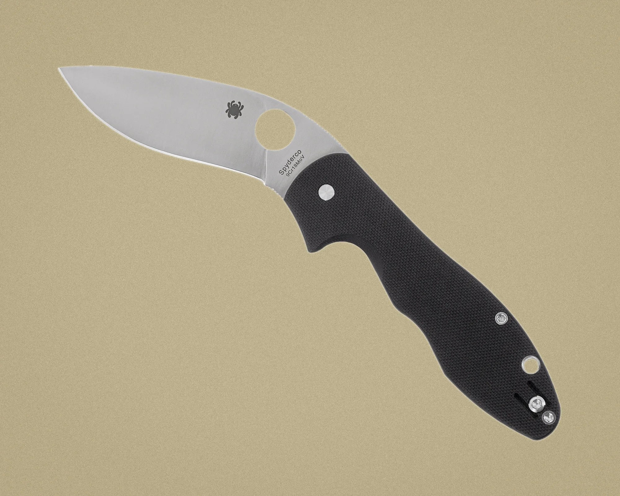 Folding knife with a stainless steel blade and black textured handle, featuring a circular thumb hole near the blade base.