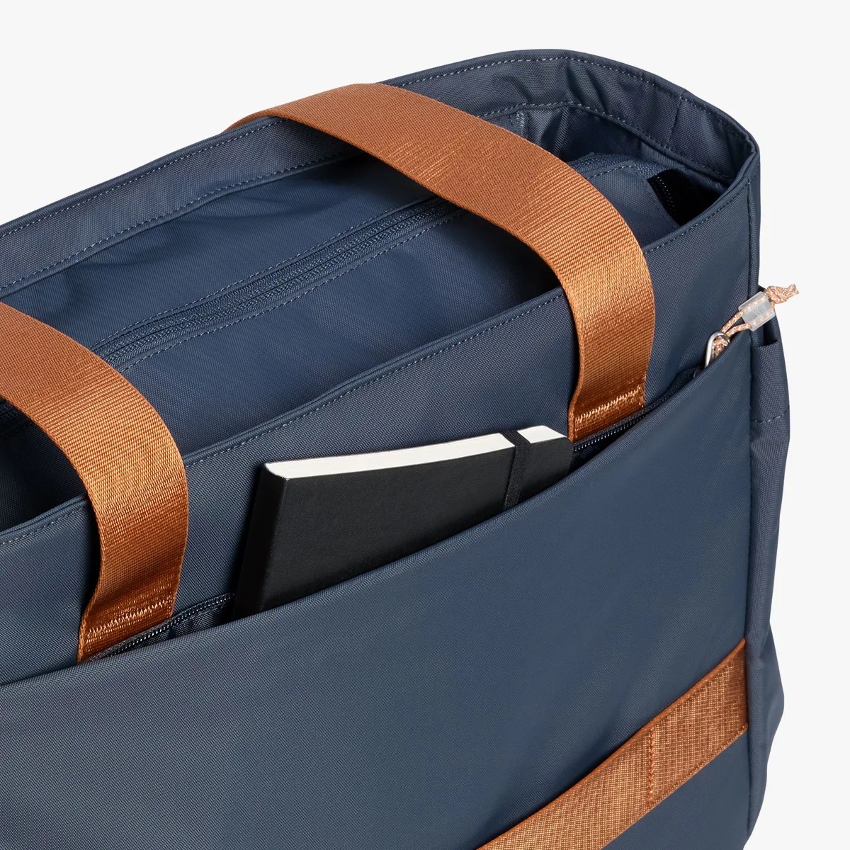 Navy blue tote bag with brown handles and a black notebook partially visible in the front pocket.