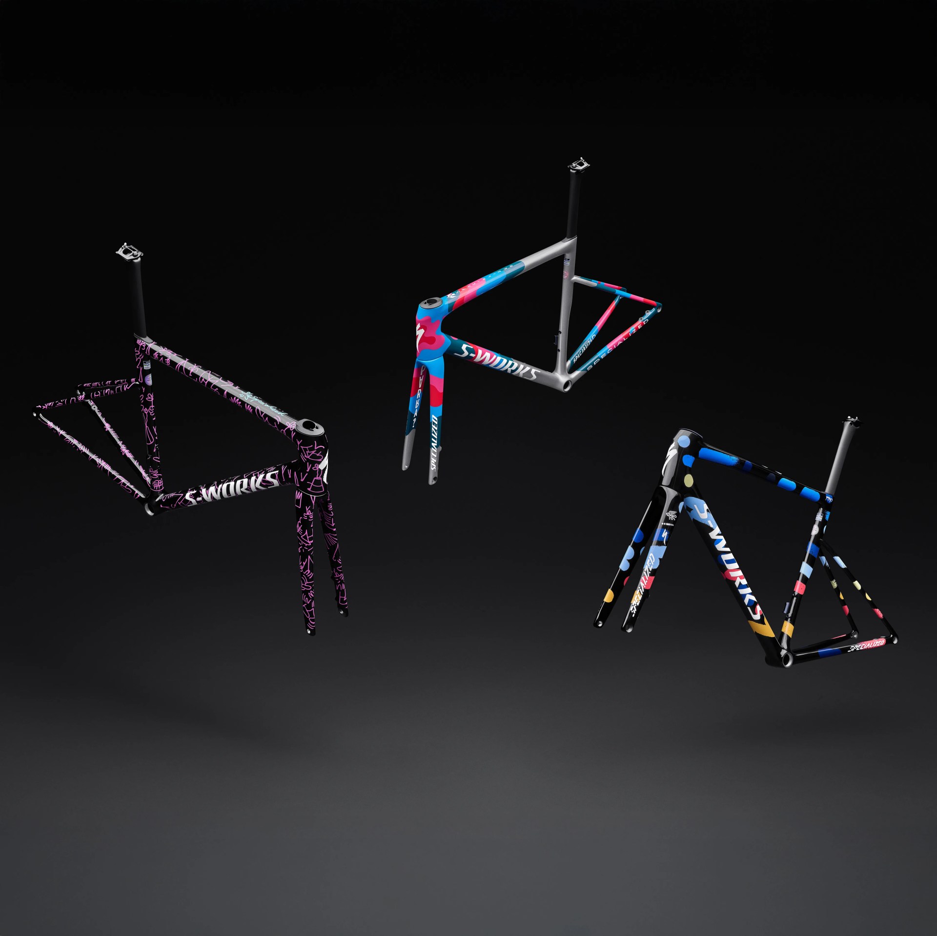 Three colorful Specialized S-Works bicycle frames with forks, each featuring unique abstract patterns, displayed against a black background.