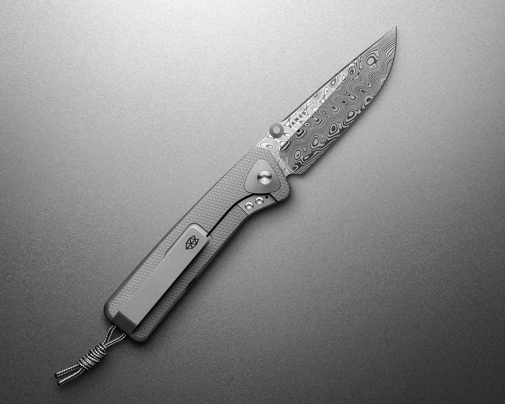 Folding knife with a patterned Damascus steel blade and textured gray handle with a pocket clip and lanyard.