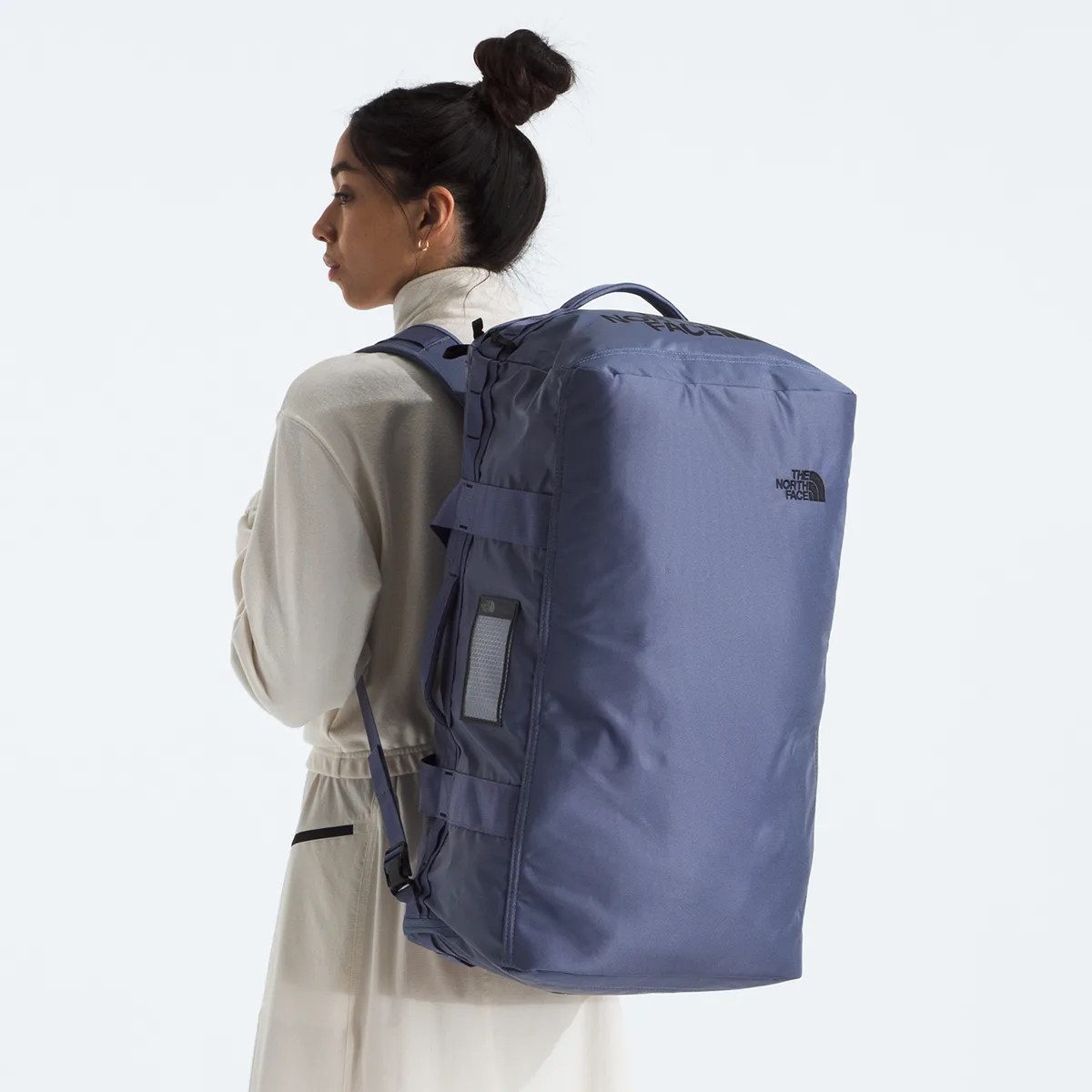 Blue The North Face duffel backpack worn by a person in a light-colored outfit.