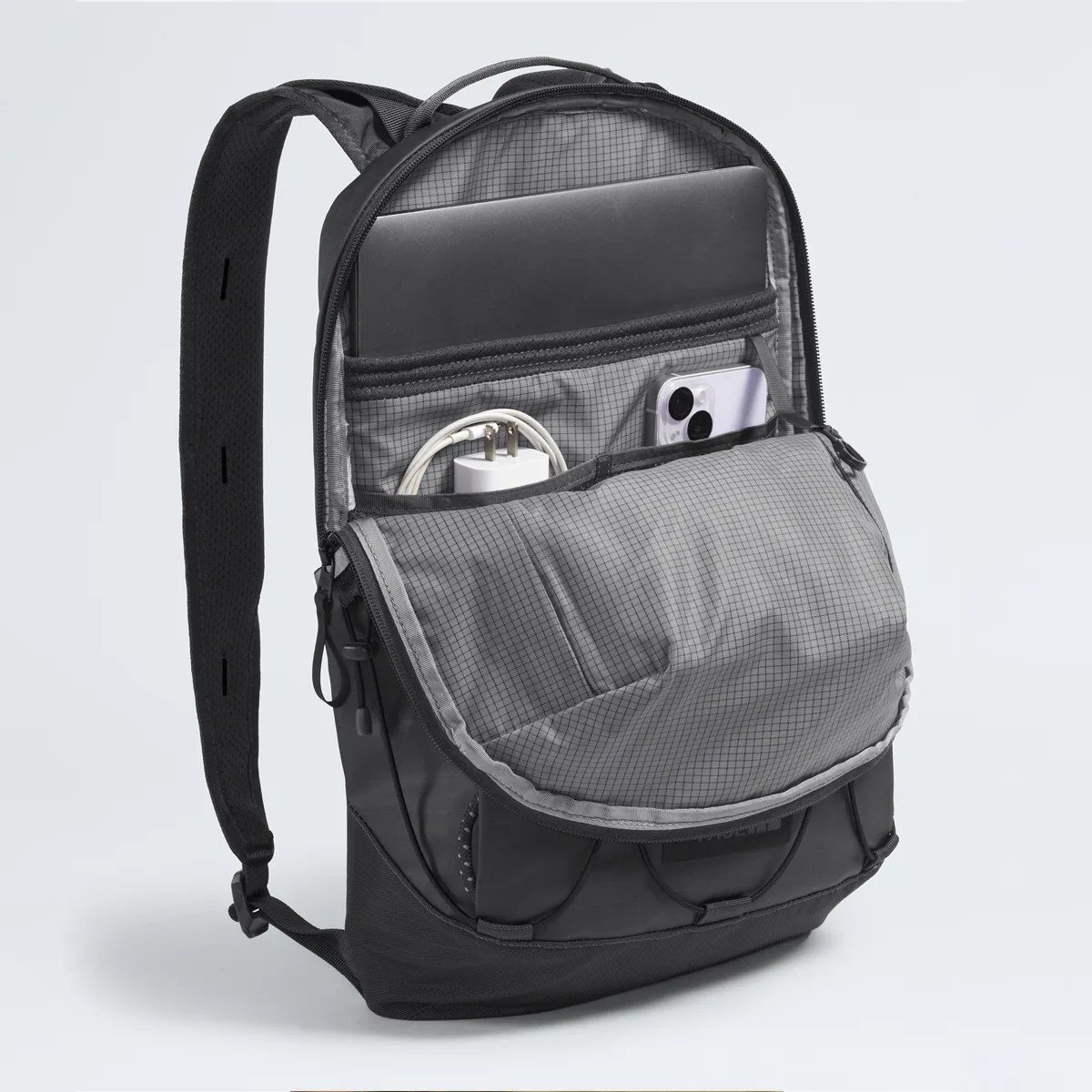 Black and gray backpack with padded interior compartments holding a laptop, phone, and charger.