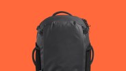 Black backpack with padded handle and side straps against an orange background.