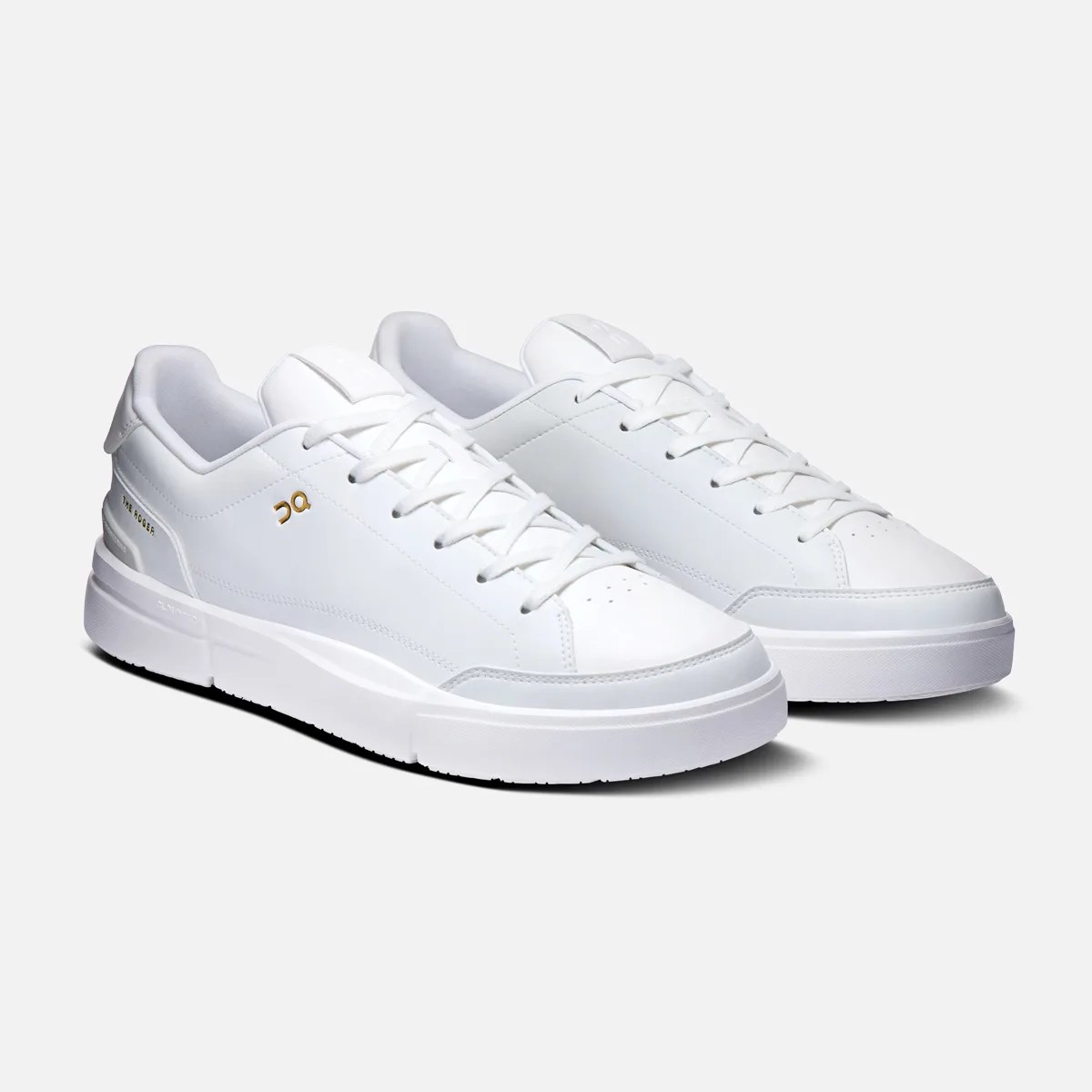Pair of white low-top sneakers with white laces and gold "On" logo on the side.
