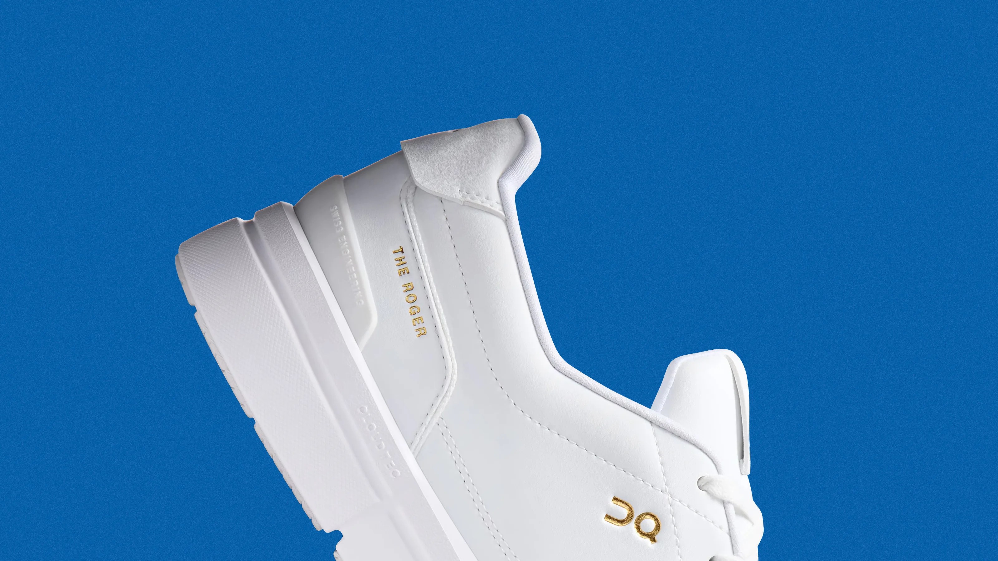 White sneaker with gold "THE ROGER" and "OC" logos on the side against a blue background.